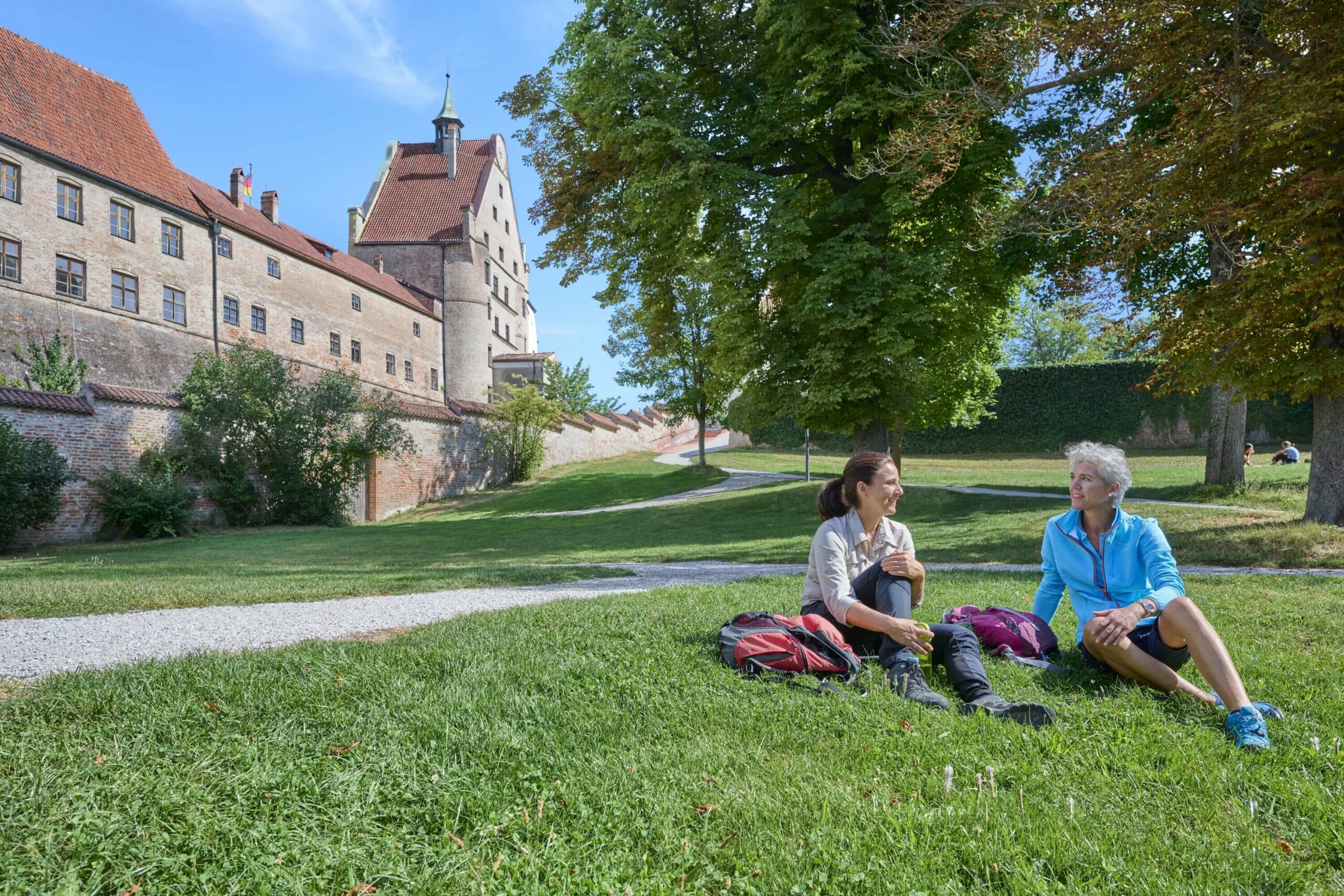 Zwei Wanderinnen im Gras auf Burg Trausnitz Landshuter Höhenweg