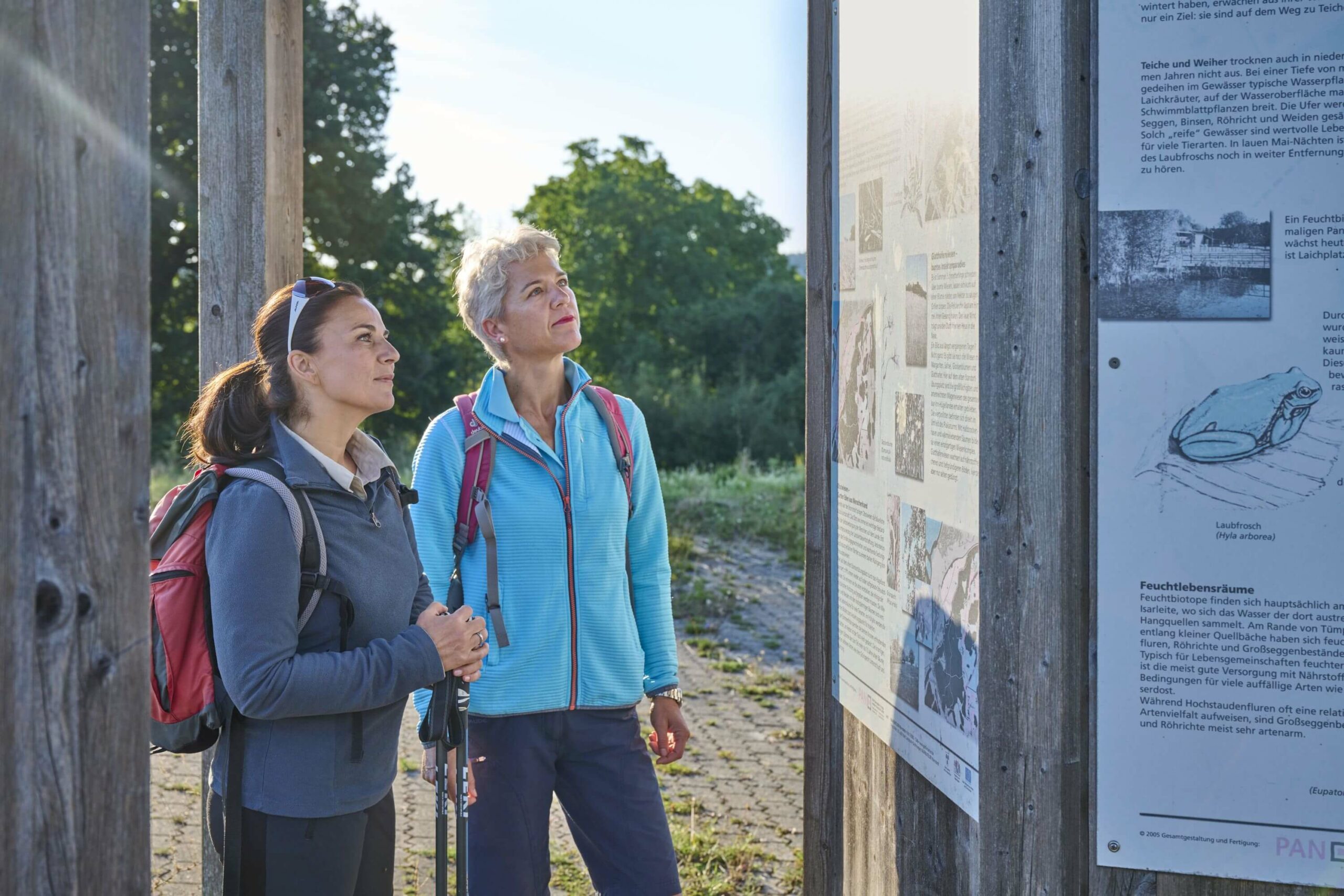 Zwei Wanderinnen vor Infotafel Standortübungsplatz Landshuter Höhenweg